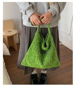 Detail van de groene boucle wollen shopper met driehoekig ontwerp en geweven label