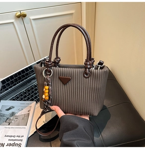 Détail du sac cabas plissé marron foncé avec logo triangle et pompon perlé