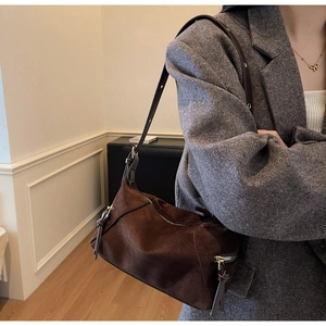 Detail of dark brown suede shoulder bag with elegant knot zipper and gold hardware