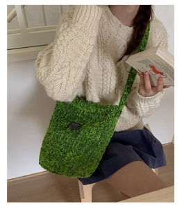 Detailansicht der grasgrünen Plüsch-Beuteltasche mit schwarzem Mode-Logo-Etikett