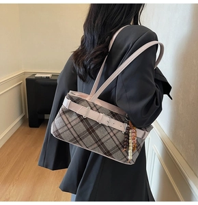 Detail of checkered plaid underarm bag with pink leather strap and colorful bead tassel