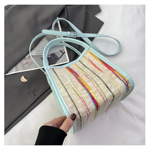 Detalle de bolso tejido a rayas de colores con correa y asa de cuero azul claro