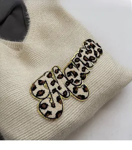 Close-up of leopard print letter applique with gold embroidery on beige canvas bag