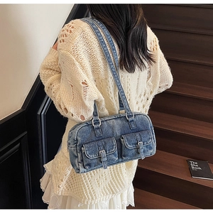 Close-up of vintage blue denim shoulder bag featuring double flap pockets and metal buckles