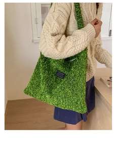 Groene wollen emmertas met 'FASHION INSTINCT'-label gedragen over de schouder