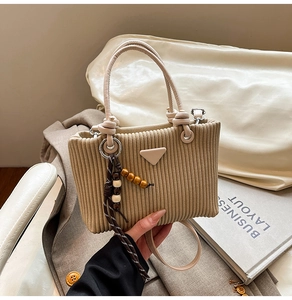 Vue détaillée du sac seau en velours côtelé beige avec pompon en perles de bois et texture