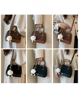 Detail view of the retro shell bag with bamboo handles and plush charm accessory