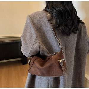 Brown suede dumpling bag on a model showing drape and minimalist retro shoulder style