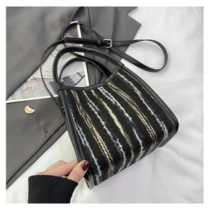 Detalle de la textura tejida a rayas y el asa de cuero de este elegante bolso cubo