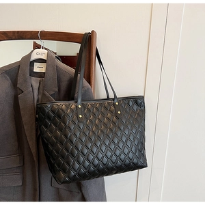 Close-up of black quilted tote bag with diamond pattern and metal rivet details