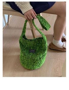 Detail einer grünen Plüsch-Tragetasche mit Modeetikett und strukturierter Strickoptik