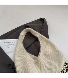 Detailed close-up of a cozy beige knitted tote bag with leopard print side accents