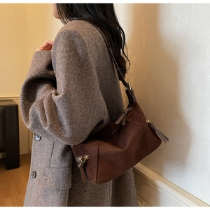 Close-up of vintage brown suede shoulder bag with bronze hardware and zipper detail