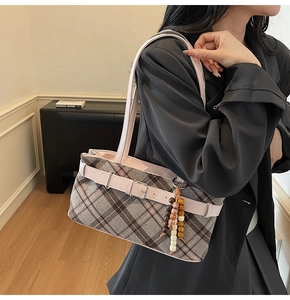 Detail of plaid tote bag featuring a leather buckle and ethnic beaded tassel charm