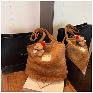 Detail der braunen Plüschtasche mit gewebtem Gurt und Teddybär-Anhänger im Weihnachtslook