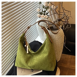 Détail du sac hobo en daim vert avec bandoulière marron et perles décoratives en bois