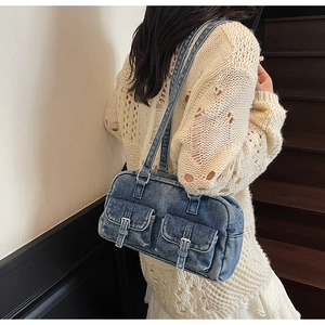Detail of vintage blue denim shoulder bag featuring dual pockets and Y2K metal buckles