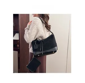Detail of a black suede and leather patchwork shoulder bag with a small detachable pouch