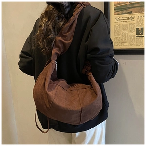 Close-up of caramel suede crossbody bag with pleated strap and crescent half-moon shape