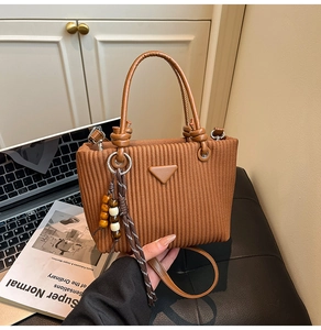Détail du sac seau en velours côtelé marron avec patch cuir, breloque en bois et sangle