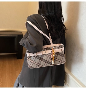 Detail view of retro plaid fabric bag with pink leather strap and beaded charm pendant