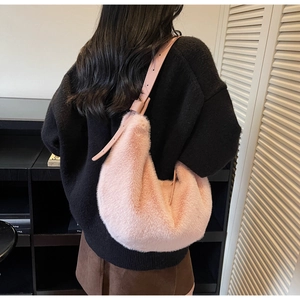 Pink plush faux fur crescent shoulder bag with adjustable strap worn by a model