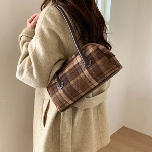 Gros plan du sac à bandoulière à carreaux marron en tissu peluche et poignée en cuir