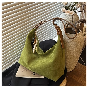Détail du sac hobo en daim vert avec pendentif en perles et bandoulière en cuir