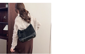 Retro black leather bucket bag with fringe detail and metal studs on the base in home setting