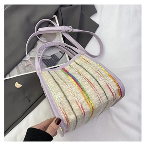 Detalle del bolso de rayas tejidas de colores con asa y bandolera de cuero morado