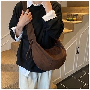 Detail view of large brown suede crescent bag with a soft texture and wide shoulder strap