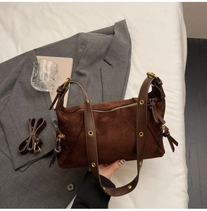 Detail of dark brown suede tote bag with gold metal eyelets and tassel zipper detail