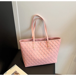 Detail of pink quilted tote bag showing fine faux leather texture and golden metal rivets