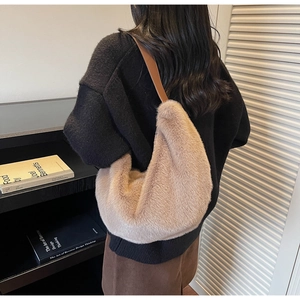 Detailed back view of a plush dumpling bag with brown leather strap worn by a model