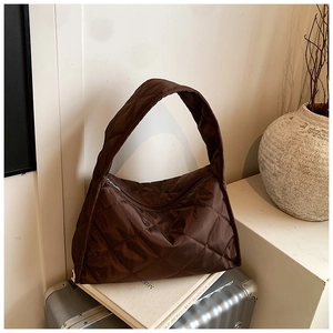 Detailed view of brown quilted hobo bag with zip closure on minimalist luggage setup