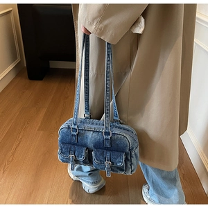 Blue denim underarm bag with vintage buckle pockets styled with a trench coat