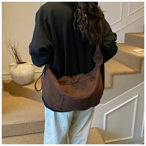 Detail of the soft dark brown suede hobo bag texture and wide integrated shoulder strap