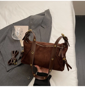 Detail showing deep brown suede texture and golden metal eyelets on the bag strap