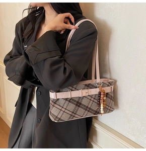 Detail view of vintage plaid shoulder bag with wooden bead charm on a grey blazer