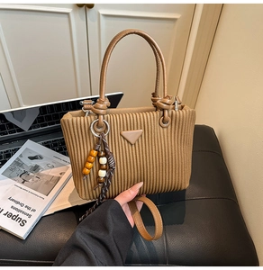 Vue détaillée du sac seau en velours côtelé marron avec poignées en cuir et pompon