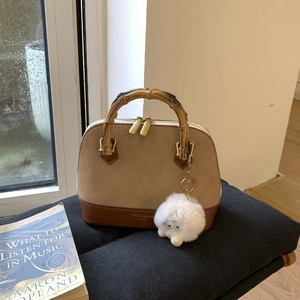Close-up of shell bag featuring bamboo handle, suede texture, and plush sheep charm