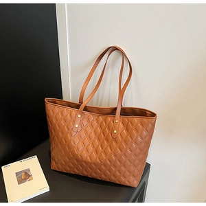 Detail of caramel brown quilted tote bag with large capacity and gold rivet hardware