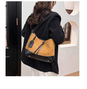 Detail view of large caramel suede and black leather shoulder bag with gold metal feet