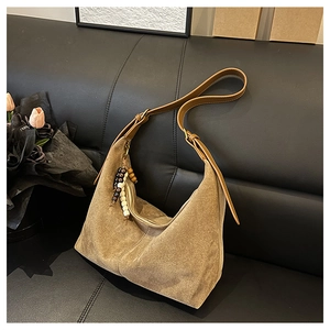 Gros plan d'un sac cabas en daim kaki avec pendentif en perles de bois sur canapé