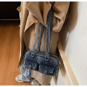 Side view of a vintage denim shoulder bag with multi-pocket details on a model
