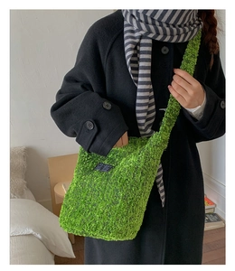 Detail der hellgrünen Plüsch-Eimertasche mit einem schwarzen Fashion-Webetikett darauf