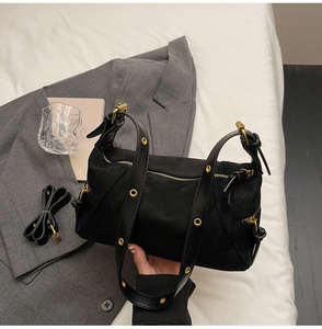 Detail view of black suede dumpling bag featuring gold eyelets and metallic hardware