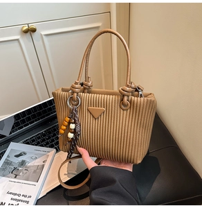 Détail du sac plissé avec poignée nouée et breloque en perles de bois à pompon
