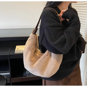 Detail view of beige faux fur hobo bag with adjustable brown leather strap on model