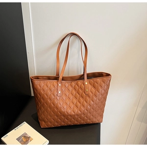 Detail of brown quilted tote bag showing matte leather texture and gold hardware